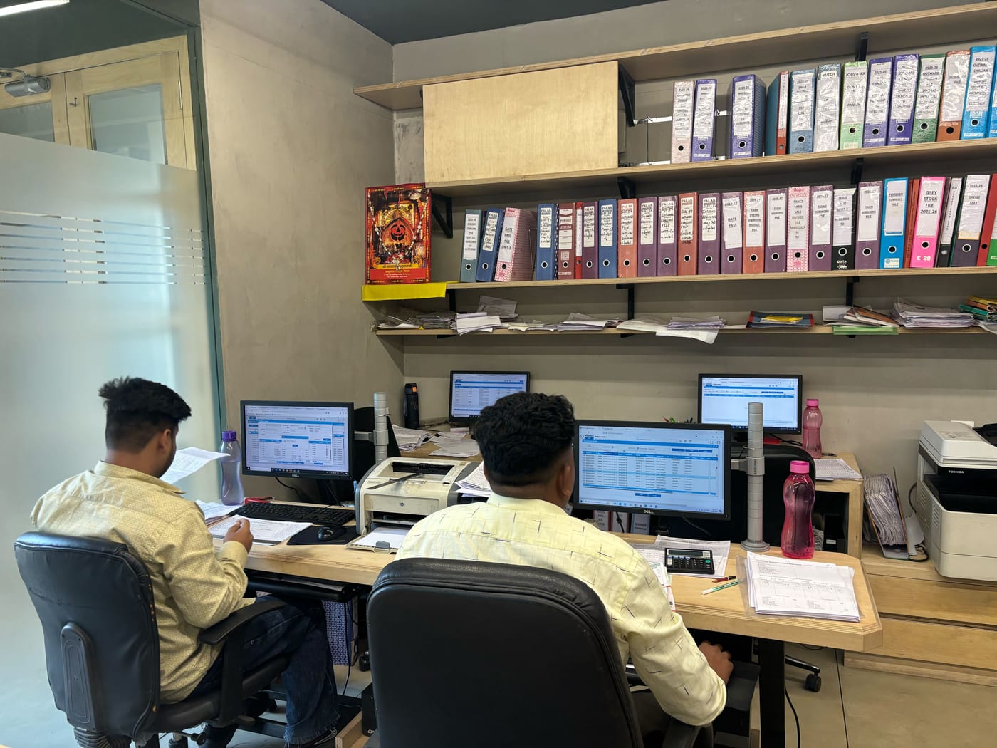 Two Kottex Industries accounts staff working on MobiOffice with shelves of binders behind them