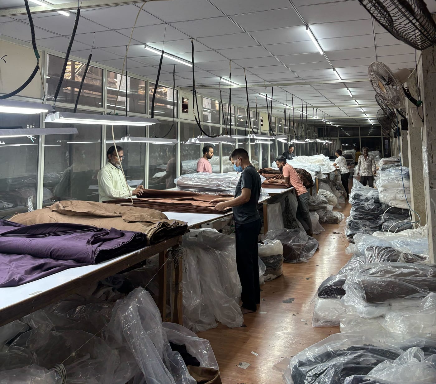 Workers inspecting and folding fabric on the Kottex Industries production floor